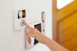 Young woman entering authorization code pin on home alarm keypad